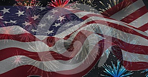 Composition of american flag billowing over red, white and blue fireworks in night sky