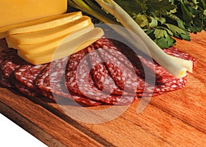Composition of appetizing sausage, cheese, greens and onions on a wooden board, isolate