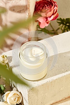 Composition with aromatic candle in jar on concrete podium. Mockup soy wax candle in natural style with flower. Scented handmade