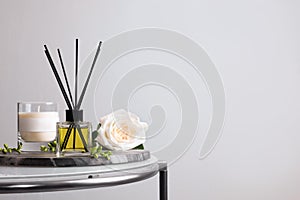 Composition with aromatic reed air freshener on glass table, space for text