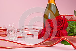 A composition of a beautiful bouquet of roses, candles, glasses and a bottle of champagne creates a romantic card. The concept of