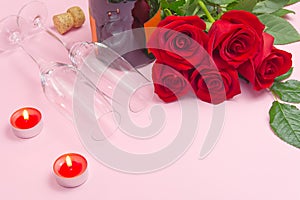 A composition of a beautiful bouquet of roses, candles, glasses and a bottle of champagne creates a romantic card. The concept of