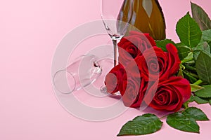 A composition of a beautiful bouquet of roses, candles, glasses and a bottle of champagne creates a romantic card. The concept of