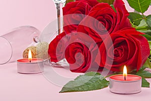 A composition of a beautiful bouquet of roses, candles, glasses and a bottle of champagne creates a romantic card. The concept of