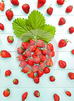Composition of big figure strawberry is laid out of strawberries with green leaf. Freshly berries, sunny summer day. Ripe red