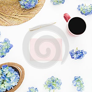 Composition of blue flowers with straw, diary and mug of coffee on white background. Flat lay