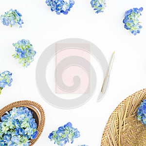 Composition of blue flowers with straw, diary and mug of coffee on white background. Flat lay, top view