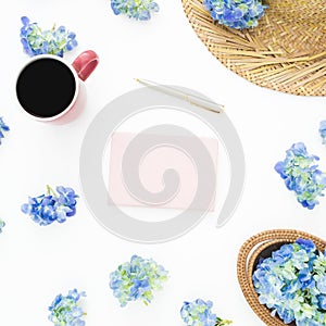 Composition of blue flowers with straw, diary and mug of coffee on white background. Flat lay, top view. Floral background