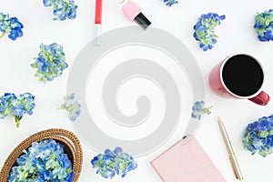 Composition of blue flowers with straw, diary and mug of coffee on white. Flat lay, top view