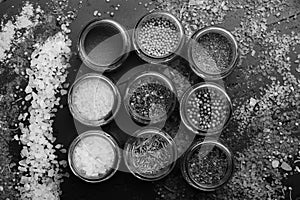 Composition of bottles with colored herbs and spices. Set of spices on dark grey background. Glass jars