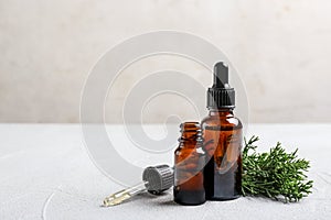 Composition with bottles of conifer essential oil on light table.