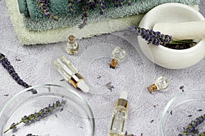 Composition of bottles with lavender oil, lavender flowers, mortar and pestle and petri dishes. Natural cosmetics concept