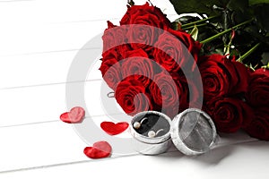 Composition from a bouquet of beautiful red roses and a gift jewelry box on the background.