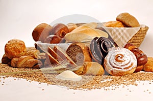 Composition with bread and rolls in wicker basket, combination of sweet pastries for bakery or market with wheat