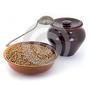 The composition of the Buckwheat groats in a clay pial next to a clay pot and a copper spoon,