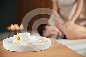 Composition with candles and blurred man receiving massage in spa salon