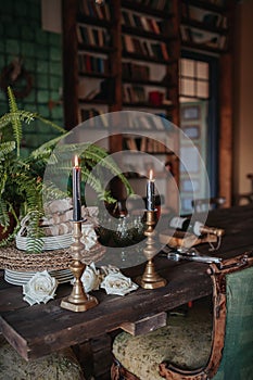 Composition of candlesticks with candles, flowers and dishes on a blurred interior background