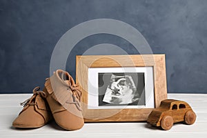 Composition with child`s booties, ultrasound photo and toy on table