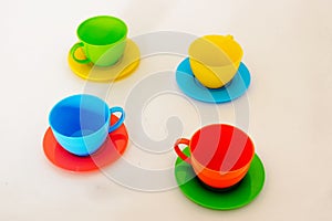 Composition from a children`s plastic service, consisting of four multi-colored tea cups with saucers