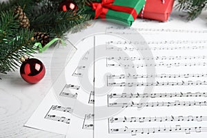 Composition with Christmas music sheets with notes on white wooden background, closeup