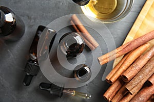 Composition with cinnamon essential oil on grey table, flat