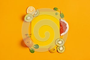 Composition of citrus fruit, orange, lemon and kiwi on yellow background