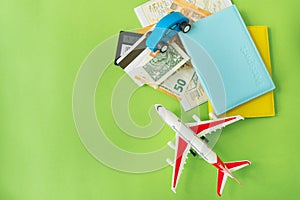 Composition from a city map with a bank card, euro, dollar banknotes, passports and a toy plane on a green background. Travel and