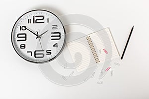 Composition with clock, notepad, paper clips and pencil. white background,flat lay. businnes concept