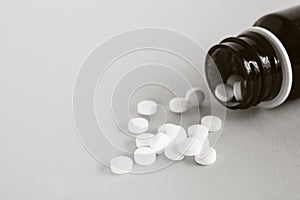 Composition close up image of white pills with bottle on white background with blank space for text.