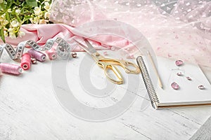 Composition with color threads and sewing accessories on white wooden background