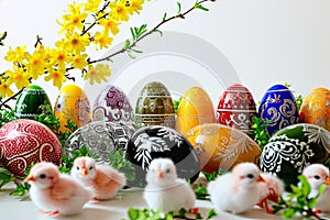 A composition of colourful Easter eggs and forsythia branches on a white trle.