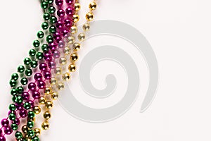 Composition of colourful mardi gras beads on white background with copy space