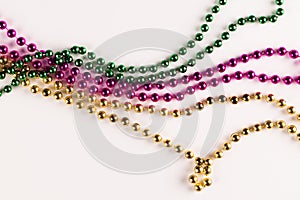 Composition of colourful mardi gras beads on white background with copy space