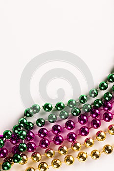 Composition of colourful mardi gras beads on white background with copy space