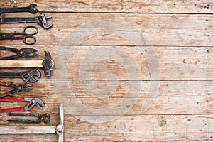 Composition of construction tools on an old battered wooden surface of tools: pliers, pipe wrench, screwdriver, hammer, metal shea