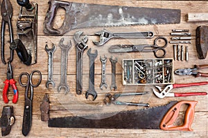 Composition of construction tools on an old battered wooden surface of tools: pliers, pipe wrench, screwdriver, hammer, metal shea