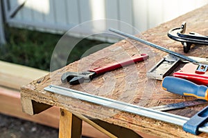 Composition of construction tools on an old wooden table of pliers, pipe wrench, screwdriver, clamps, roulette