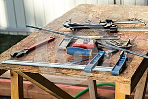 Composition of construction tools on an old wooden table of pliers, pipe wrench, screwdriver, clamps, roulette