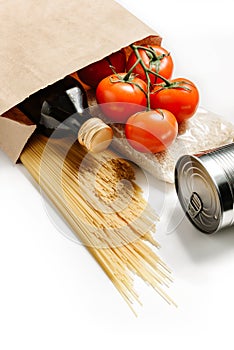 Composition with craft bag, spaghetti, tomatoes, rice, canned goods and olive oil isolated on a white background