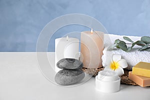 Composition with cream and burning candles on white table. Spa treatment