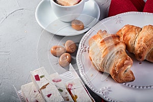 Composition of croissants on white plate, coffee with marshmallow and sweets. Breakfast or lunch. Ideal for cafe menu.