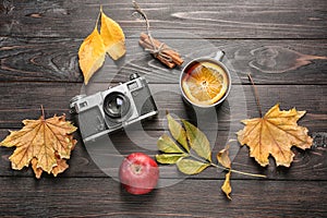 Composition with cup of delicious mulled wine, photo camera and autumn leaves on wooden background