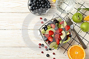 Composition cup of fresh fruit salad on white wooden table, top view