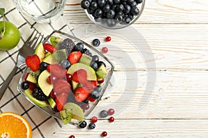 Composition with cup of fresh fruit salad on wooden table, top view