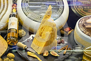 Composition of cut cheese head with with whole heads of cheese, wine, figs, knife, real scene in food market