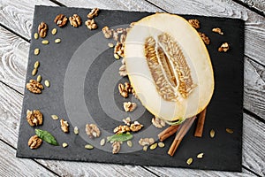 Composition of cut melon, walnuts and cinnamon. Sweet fruits and crunchy nuts on a table background. Vegetarian food