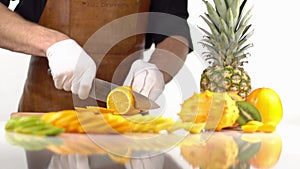 The composition of cut in slices orange fruits placed near the kiwano, persimmons and pineapple. The cooker is cutting