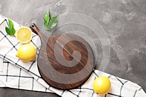 Composition of a dark wooden kitchen board, fresh lemons, a tea towel, on a marble background. Place for your text. Recipe ideas