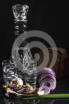 Composition with a decanter of vodka with chopped onions, garlic, bread, a herring sandwich and black bread