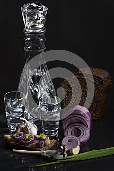 Composition with a decanter of vodka with chopped onions, garlic, bread, a herring sandwich and black bread
